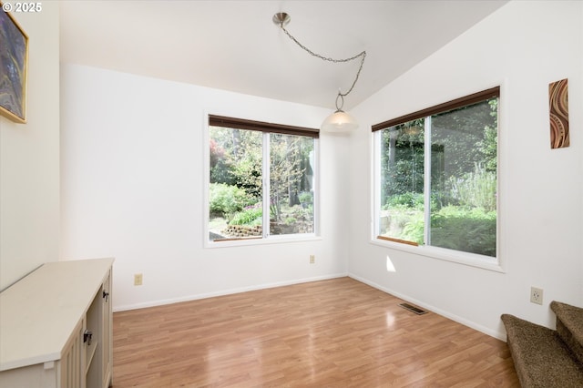 unfurnished dining area with light wood-style floors, stairway, a healthy amount of sunlight, and visible vents