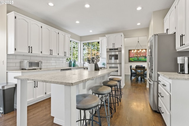 kitchen with stainless steel appliances, a center island, white cabinets, and a kitchen breakfast bar