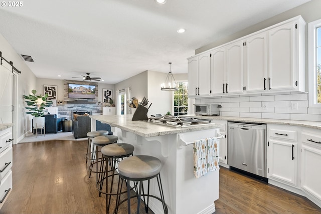 kitchen featuring white cabinetry, a kitchen island, pendant lighting, stainless steel appliances, and a barn door