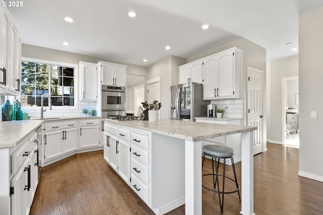 kitchen featuring sink, dark wood-type flooring, appliances with stainless steel finishes, white cabinets, and a kitchen island