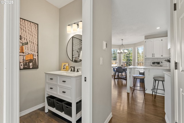 hallway featuring dark hardwood / wood-style flooring, a chandelier, and sink