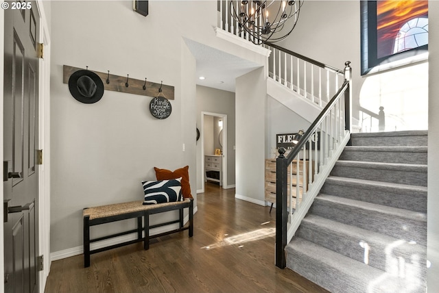 foyer with dark hardwood / wood-style flooring, an inviting chandelier, and a high ceiling