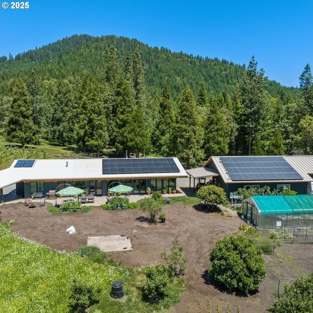 1104 Upper Cow Creek Rd, Azalea, OR 97410 - back of house featuring a view of trees, a greenhouse, an outdoor structure, and solar panels