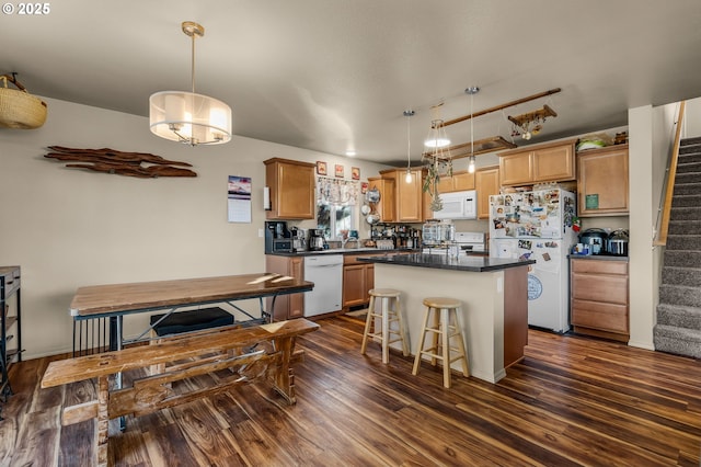 kitchen featuring dark wood-type flooring, white appliances, decorative light fixtures, and a center island