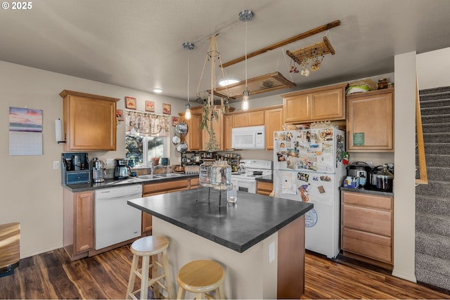 kitchen with sink, a center island, dark hardwood / wood-style flooring, pendant lighting, and white appliances