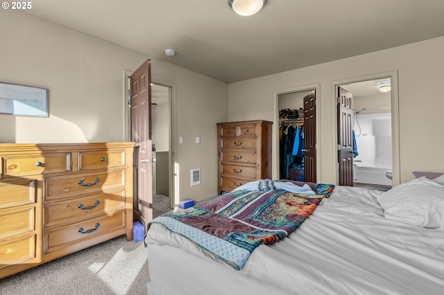 bedroom featuring a walk in closet, carpet floors, ensuite bath, and a closet