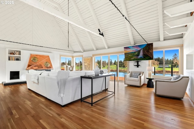 living area with wood finished floors, plenty of natural light, beamed ceiling, wood ceiling, and high vaulted ceiling
