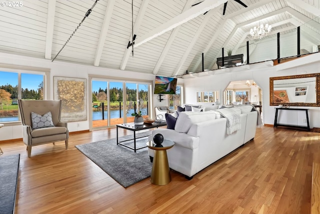 living room featuring beam ceiling, plenty of natural light, hardwood / wood-style floors, and a chandelier