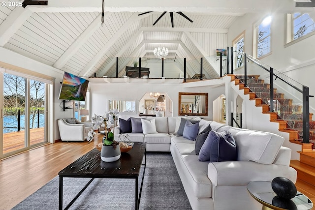 living room with a healthy amount of sunlight, hardwood / wood-style floors, high vaulted ceiling, and a chandelier