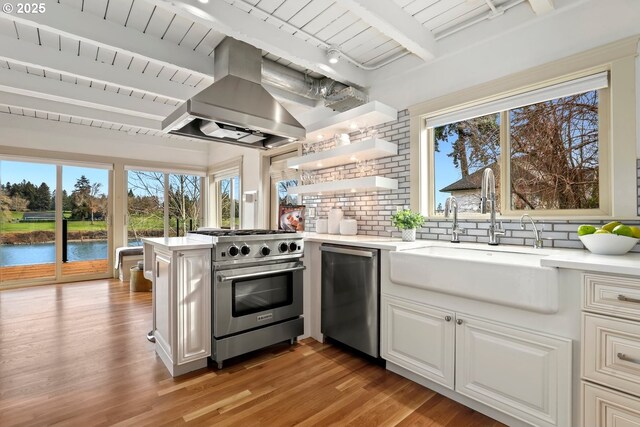 kitchen with stainless steel appliances, a sink, island exhaust hood, a peninsula, and light countertops