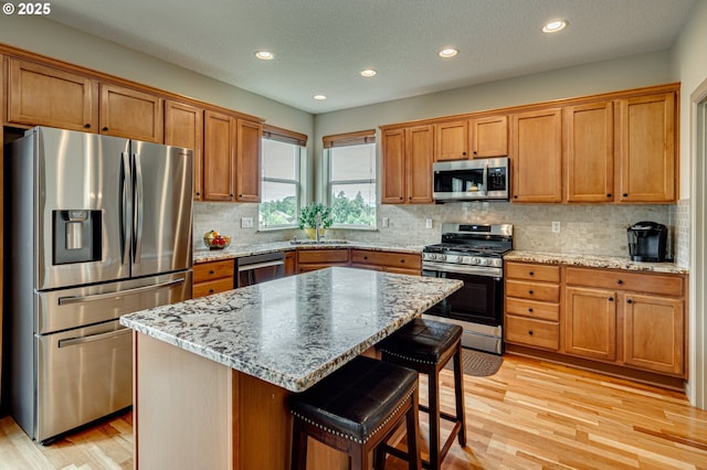 1551 S 14th Cir, Ridgefield, WA 98642 - kitchen featuring appliances with stainless steel finishes, light wood-type flooring, brown cabinets, a kitchen breakfast bar, and recessed lighting