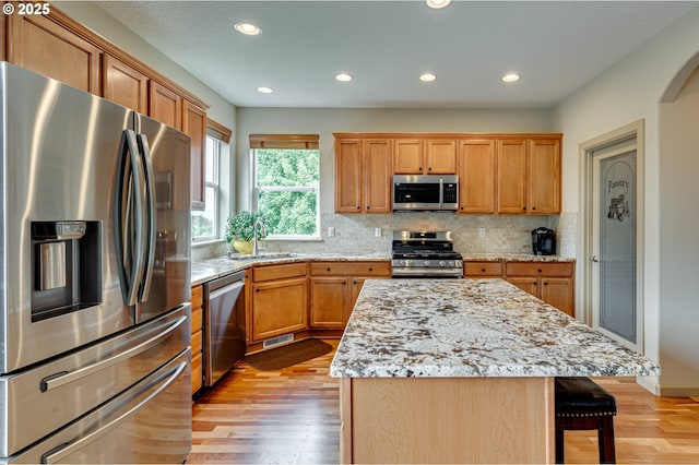 1551 S 14th Cir, Ridgefield, WA 98642 - kitchen with stainless steel appliances, recessed lighting, tasteful backsplash, light wood-style floors, and a breakfast bar area