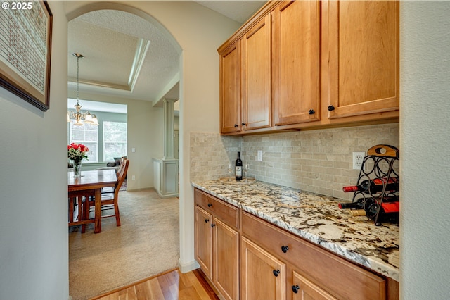 1551 S 14th Cir, Ridgefield, WA 98642 - kitchen with a textured ceiling, tasteful backsplash, light wood-style floors, arched walkways, and light stone counters