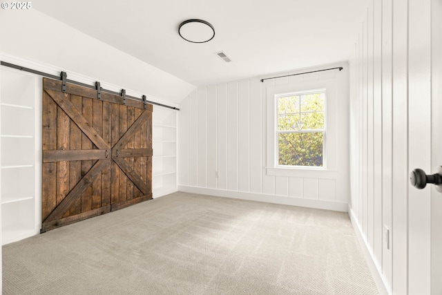 2340 SW Dolph Ct, Portland, OR 97219 - empty room featuring a barn door, carpet, vaulted ceiling, and built in features