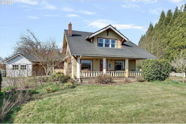 view of front of property with a front yard, covered porch, and a chimney