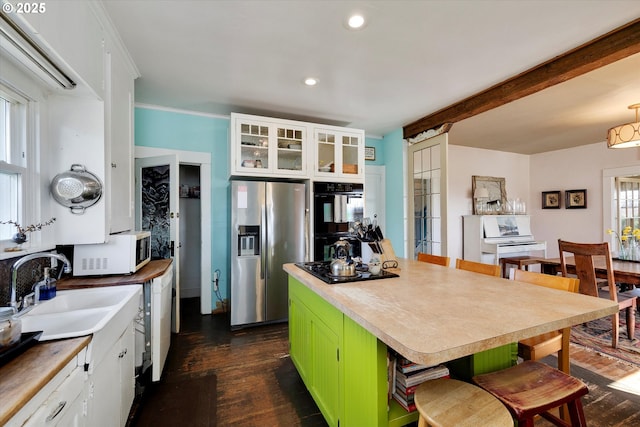 kitchen featuring a sink, a center island, dark wood-style floors, black appliances, and a kitchen bar