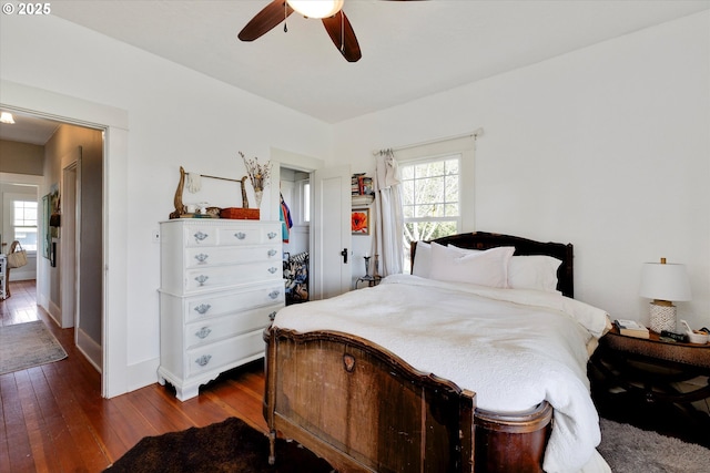 bedroom featuring ceiling fan, multiple windows, baseboards, and dark wood-style flooring