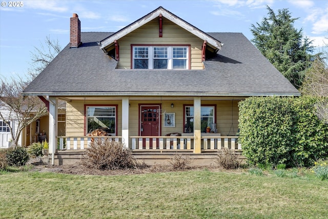 view of front of house with a porch, a shingled roof, a chimney, and a front lawn