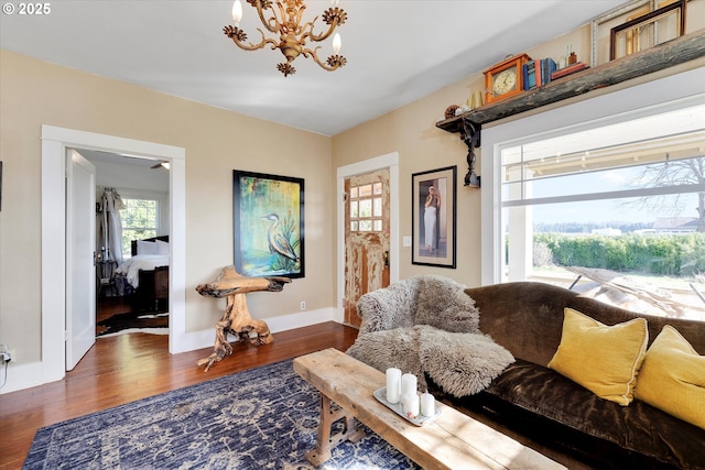 living room featuring a notable chandelier, baseboards, and wood finished floors