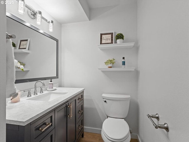 bathroom with baseboards, vanity, toilet, and wood finished floors