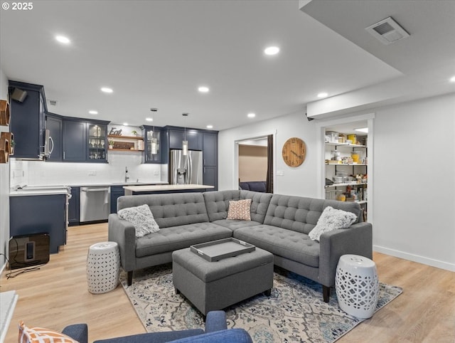 living area featuring indoor wet bar, recessed lighting, visible vents, and light wood finished floors