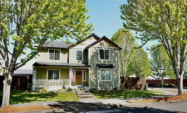 traditional-style home featuring a porch, fence, and a front yard