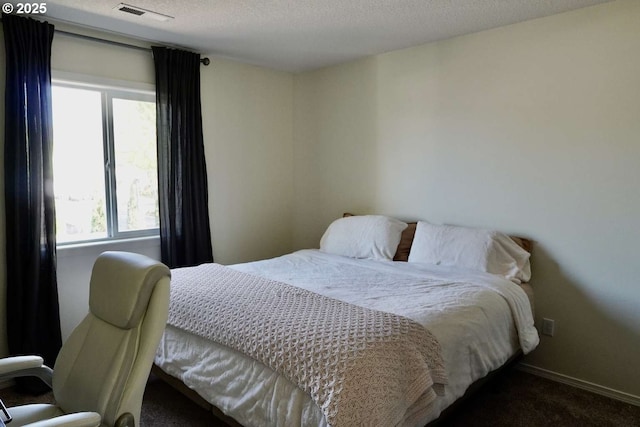 carpeted bedroom with a textured ceiling, baseboards, and visible vents