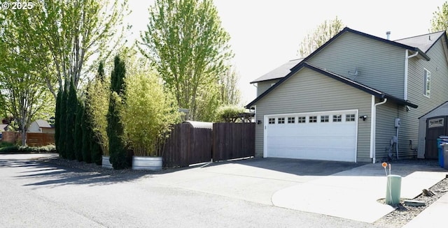 view of property exterior with an attached garage, concrete driveway, and fence