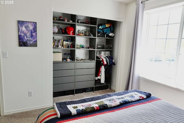 carpeted bedroom with a closet and baseboards