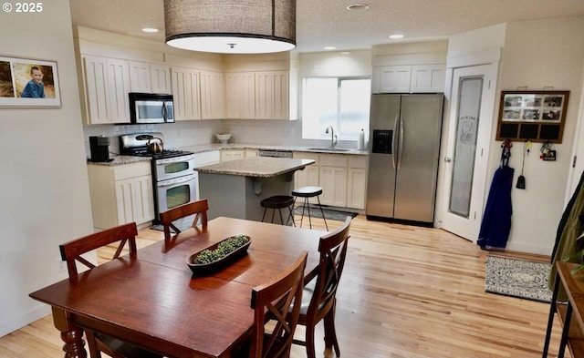 kitchen with stainless steel appliances, a sink, backsplash, recessed lighting, and light wood-style flooring