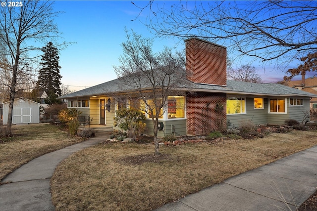 single story home featuring a yard and a storage shed