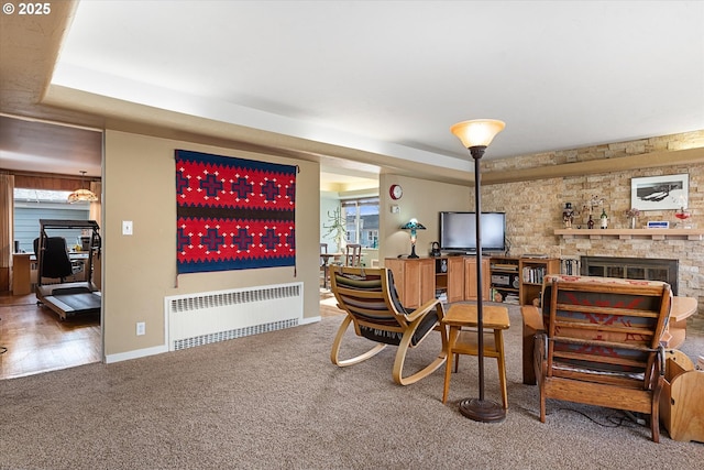 interior space with radiator, a tray ceiling, a fireplace, and carpet