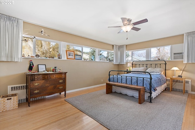 bedroom with ceiling fan, radiator, and light hardwood / wood-style flooring