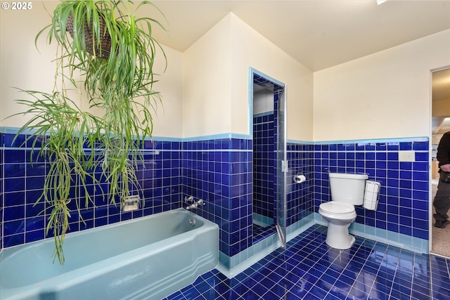 bathroom featuring tile patterned flooring, tile walls, a bathtub, and toilet