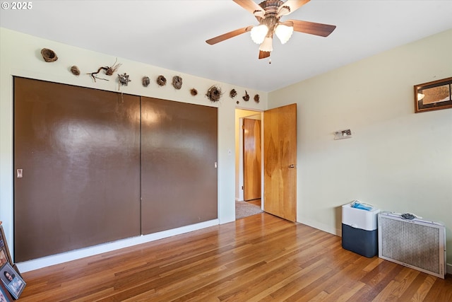 unfurnished bedroom featuring hardwood / wood-style flooring, a closet, and ceiling fan