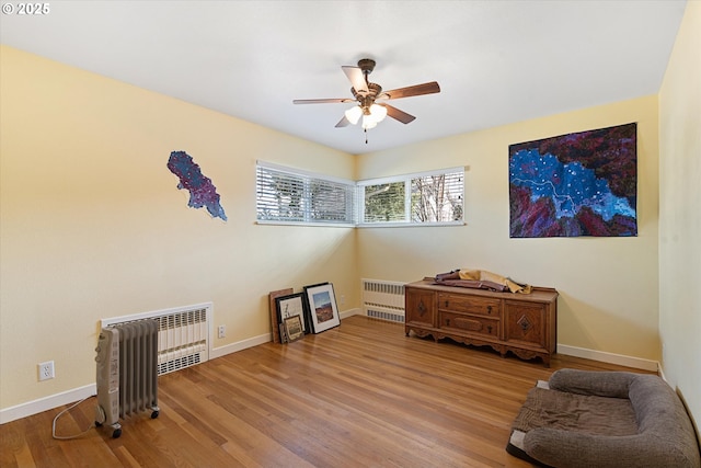 sitting room featuring hardwood / wood-style flooring, radiator heating unit, and ceiling fan