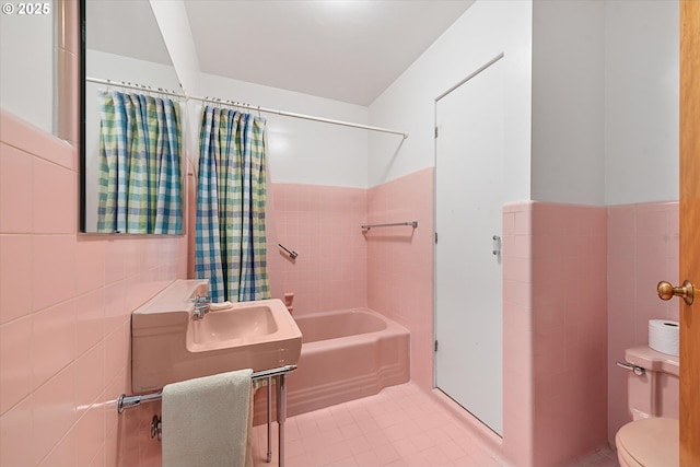 bathroom with tile patterned floors, toilet, shower / tub combo, and tile walls