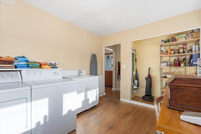 washroom featuring sink, light hardwood / wood-style flooring, washing machine and dryer, and cabinets