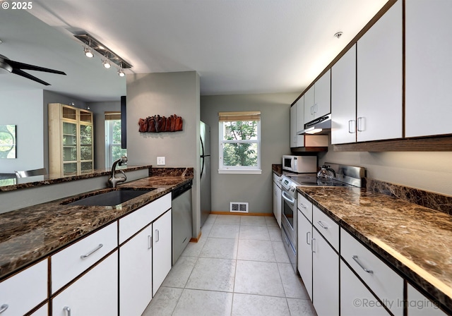 305 S Montgomery St Unit 404, Portland, OR 97201 - kitchen with appliances with stainless steel finishes, a sink, white cabinetry, dark stone counters, and under cabinet range hood