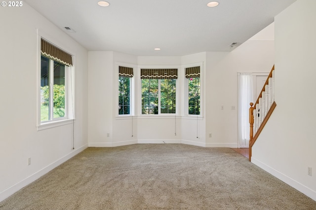 empty room with visible vents, baseboards, recessed lighting, stairway, and carpet floors