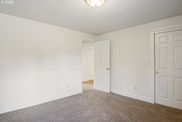 unfurnished bedroom featuring carpet, a textured ceiling, and baseboards