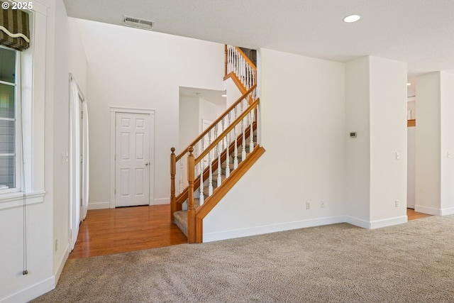 foyer featuring stairs, carpet floors, baseboards, visible vents, and recessed lighting