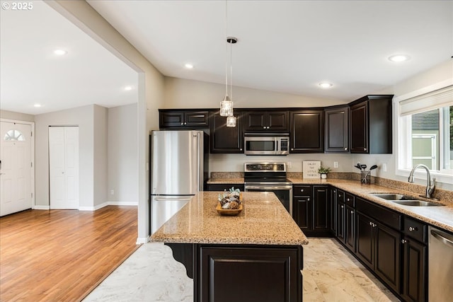 kitchen with a kitchen island, appliances with stainless steel finishes, light stone counters, a sink, and lofted ceiling