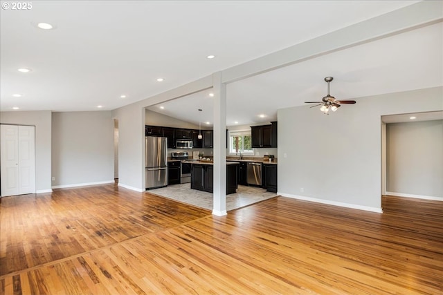 unfurnished living room featuring baseboards, a ceiling fan, light wood-style floors, recessed lighting, and vaulted ceiling
