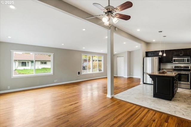 kitchen featuring open floor plan, appliances with stainless steel finishes, light wood-style floors, dark cabinets, and lofted ceiling