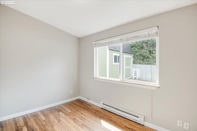 spare room with light wood-style floors, a baseboard radiator, and baseboards