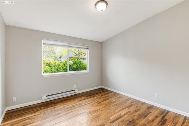unfurnished room featuring baseboards, hardwood / wood-style floors, and a baseboard heating unit