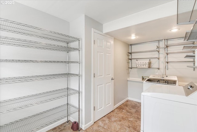 clothes washing area featuring independent washer and dryer, laundry area, and baseboards