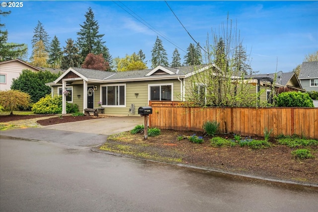 single story home with driveway and a fenced front yard