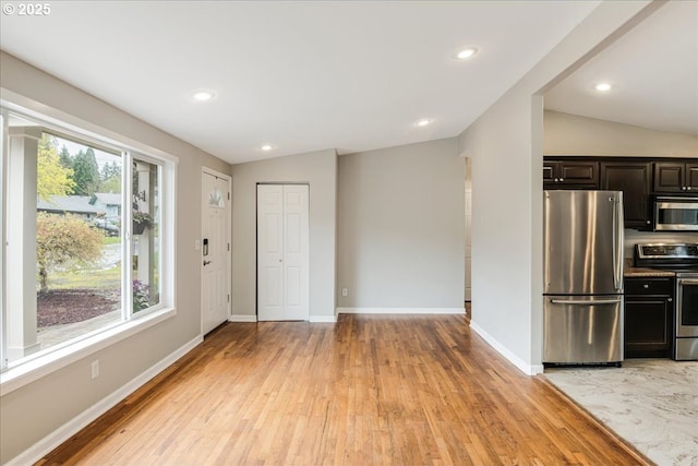interior space featuring baseboards, light wood-type flooring, appliances with stainless steel finishes, recessed lighting, and vaulted ceiling